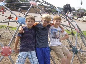 Three children posing on a playground climbing dome