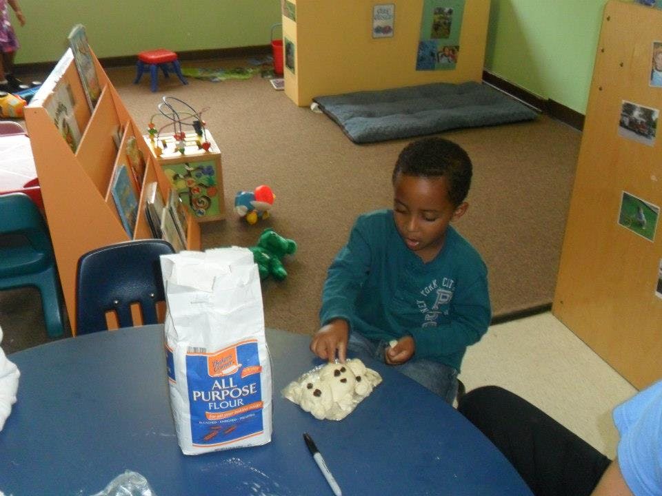 Child playing with dough and flour on a table