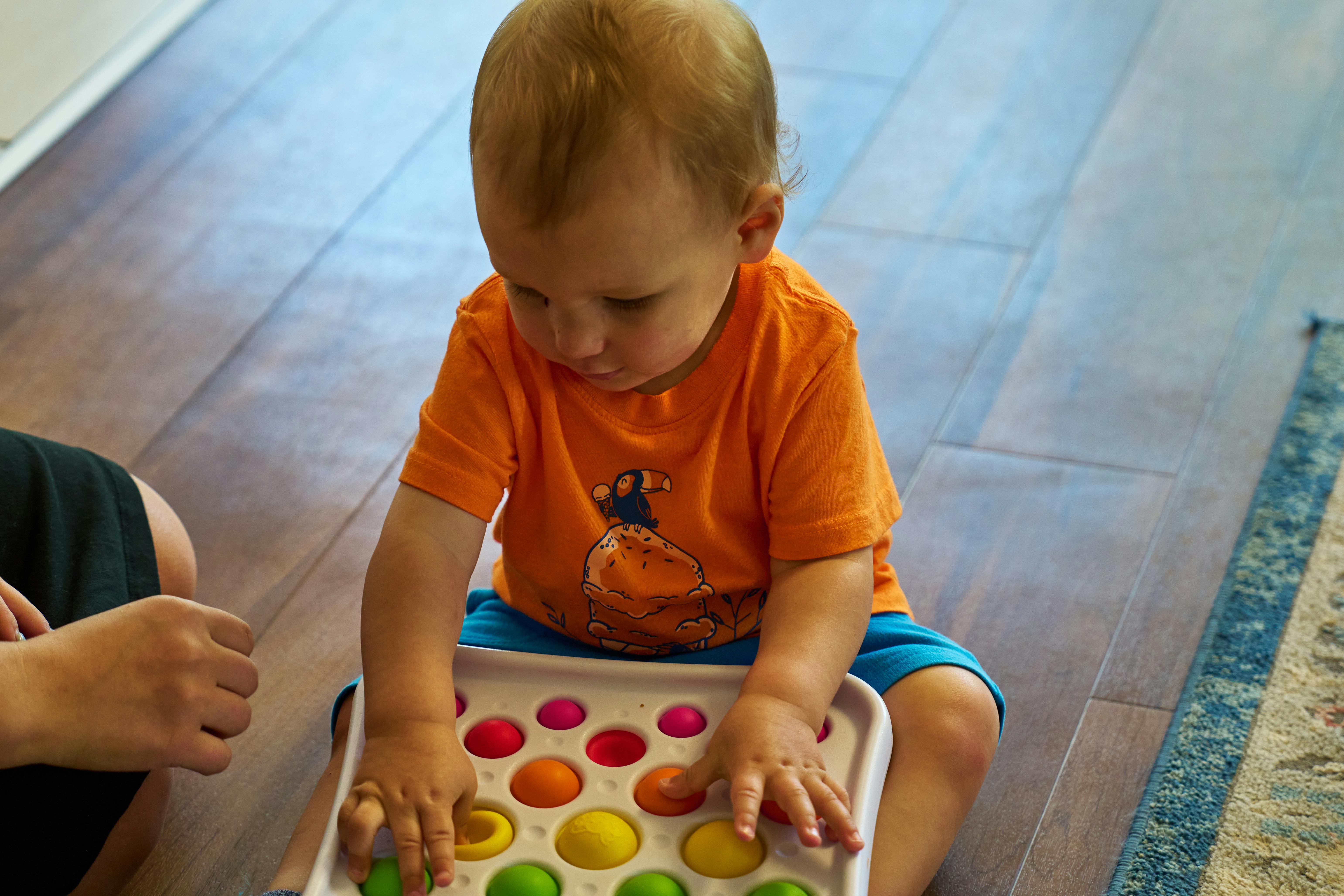 Child playing with a colorful pop-it toy
