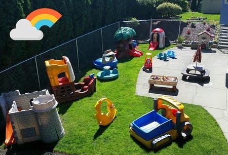 Outdoor play area with various colorful plastic toys on grass and patio