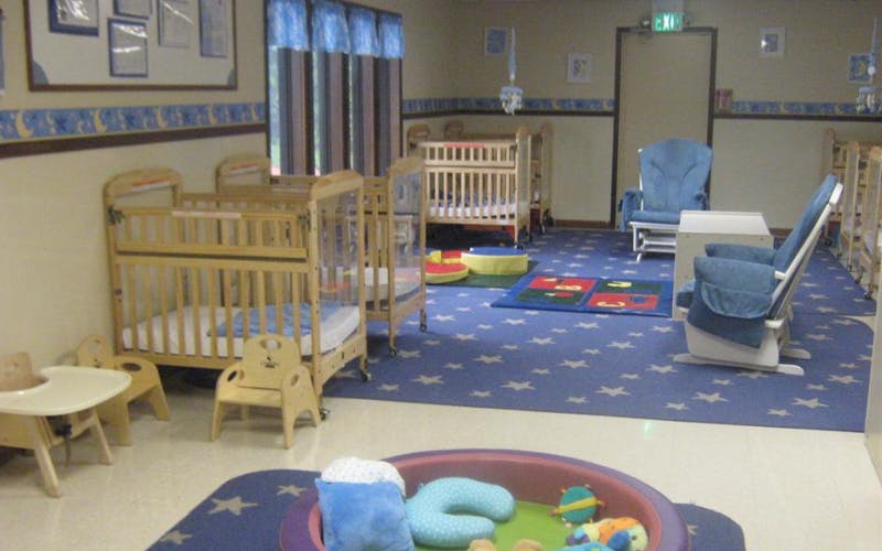 A room with several cribs, a blue star-patterned rug, and play items