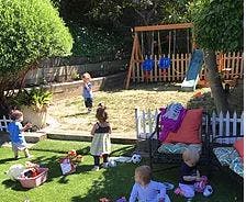 Children playing in a backyard with a swing set