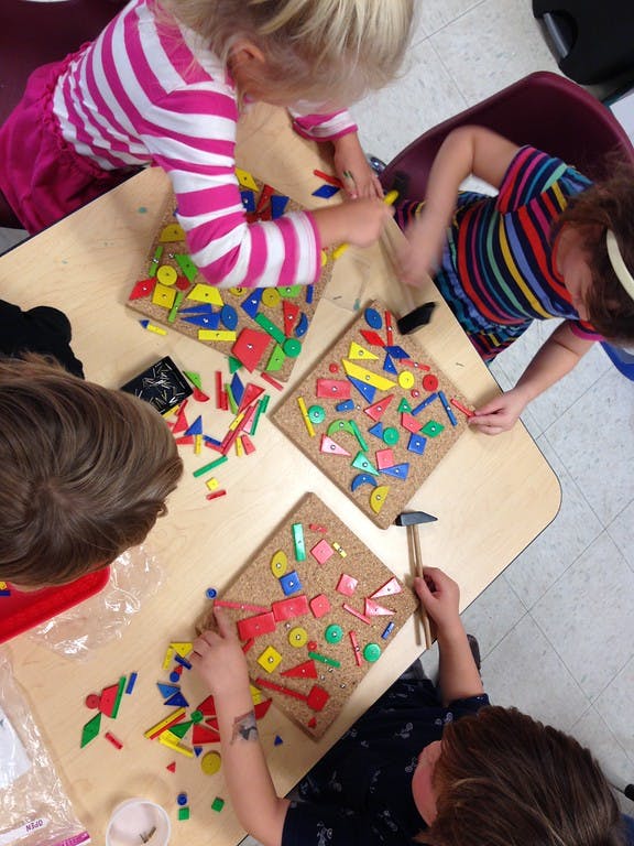Children playing with colorful shapes on cork boards in a classroom