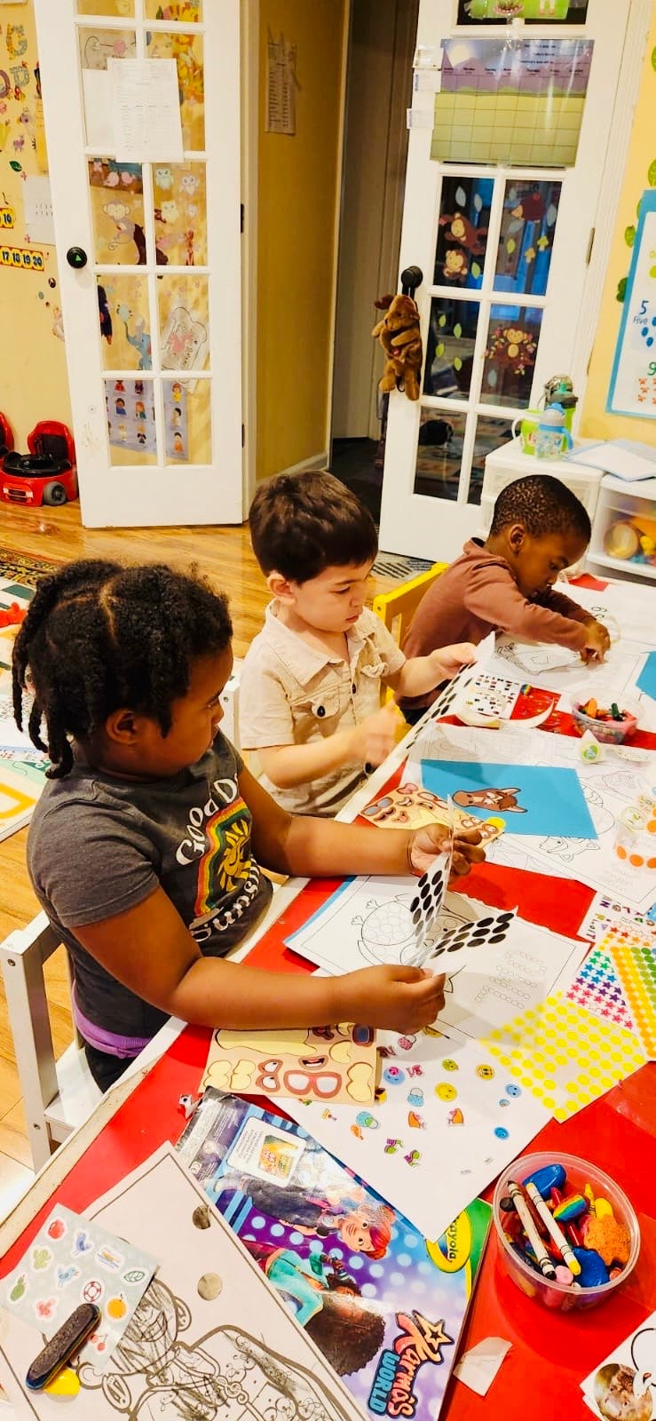 Three children sitting at a table doing crafts