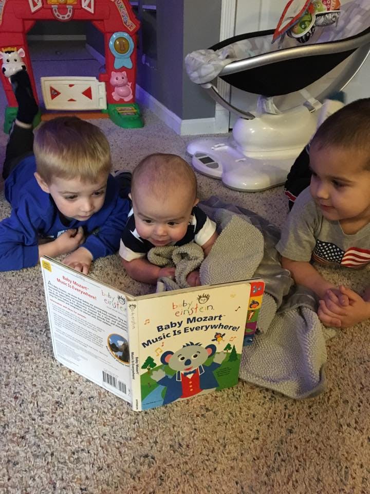 Three children looking at a book on the floor