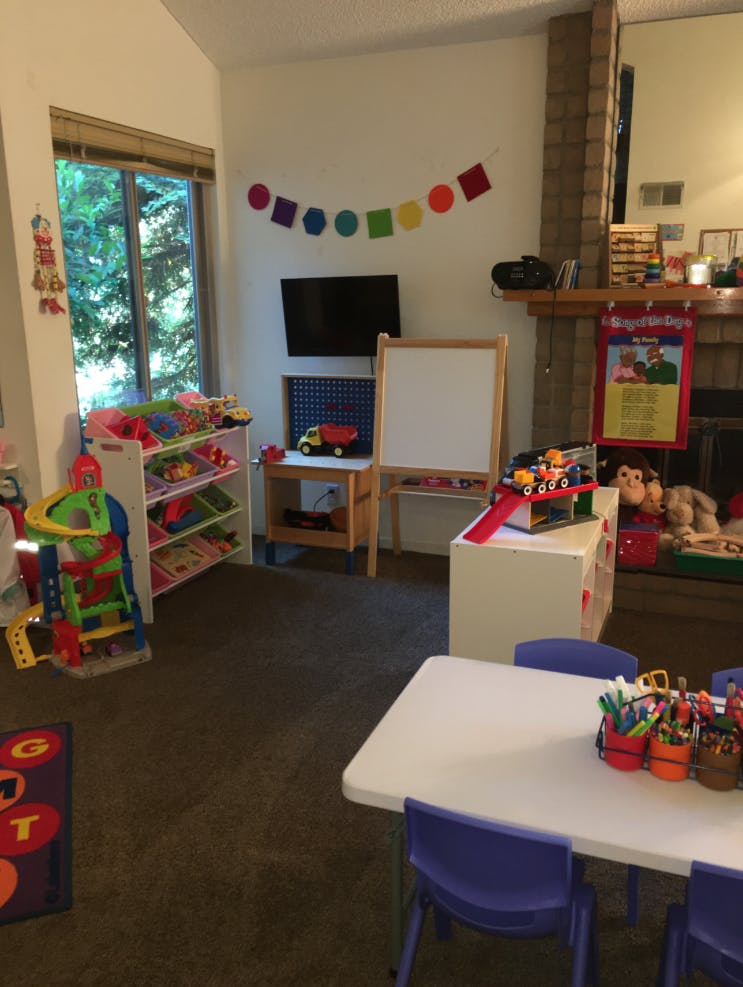 Playroom with small table and chairs, toys, and an easel