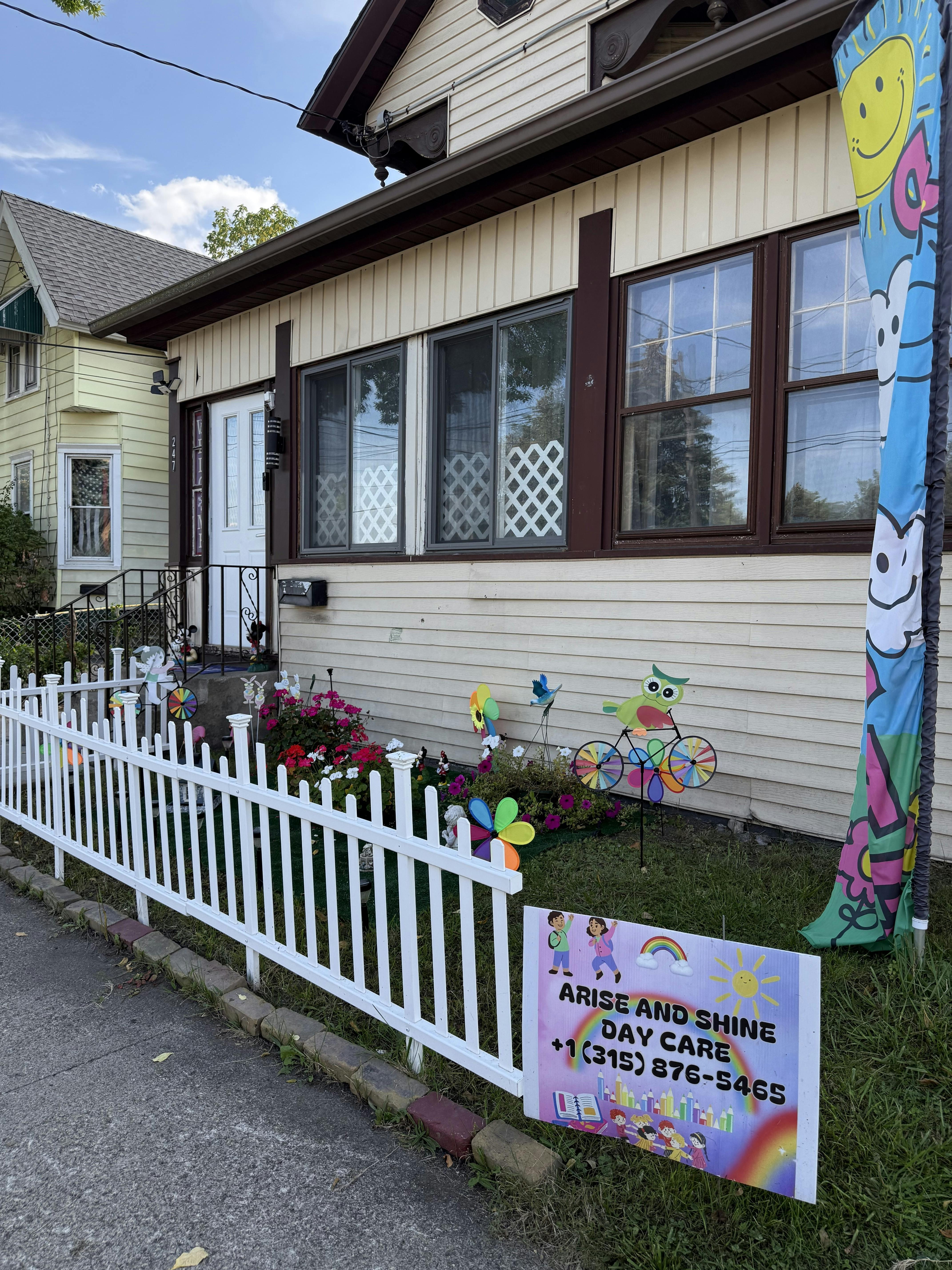House with a white picket fence and a sign for Arise and Shine Day Care