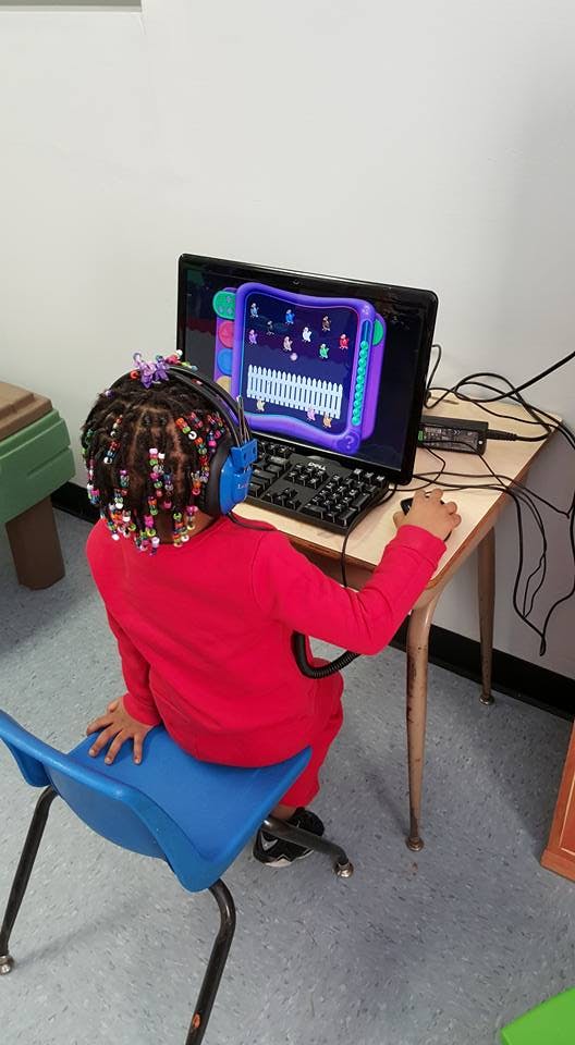 Child wearing headphones and using a computer mouse