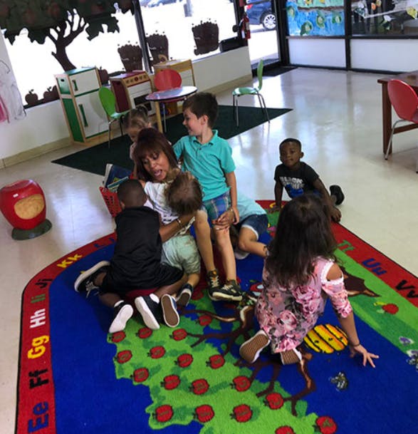 Children sitting on a colorful rug in a classroom