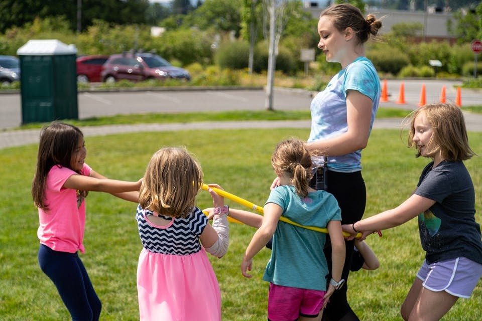 Person and children playing with hula hoops outdoors