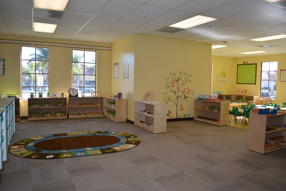 Empty classroom with a rug, shelves, and small tables