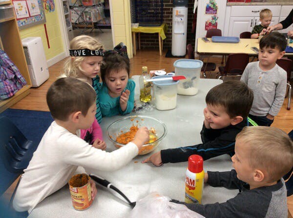 Children gathered around a table mixing ingredients in a bowl