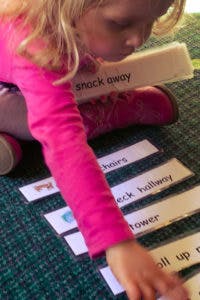 Child reaching for word cards on the floor
