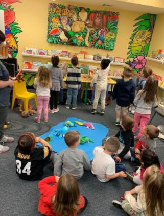 Children playing with toys on a blue mat in a classroom
