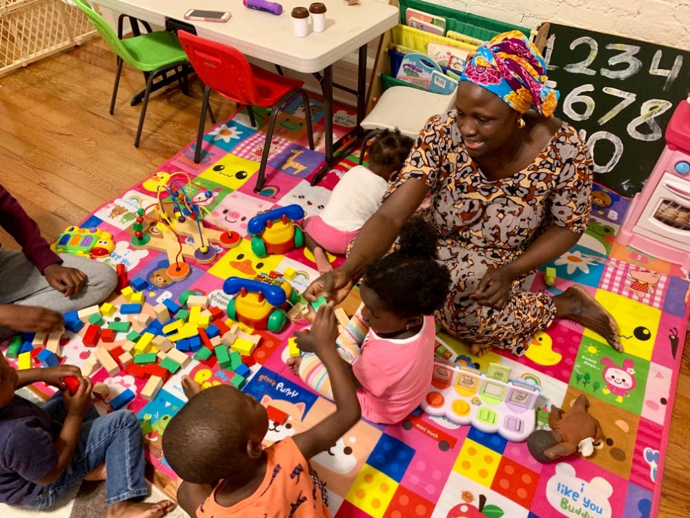 Adult and children playing with toys on a colorful mat
