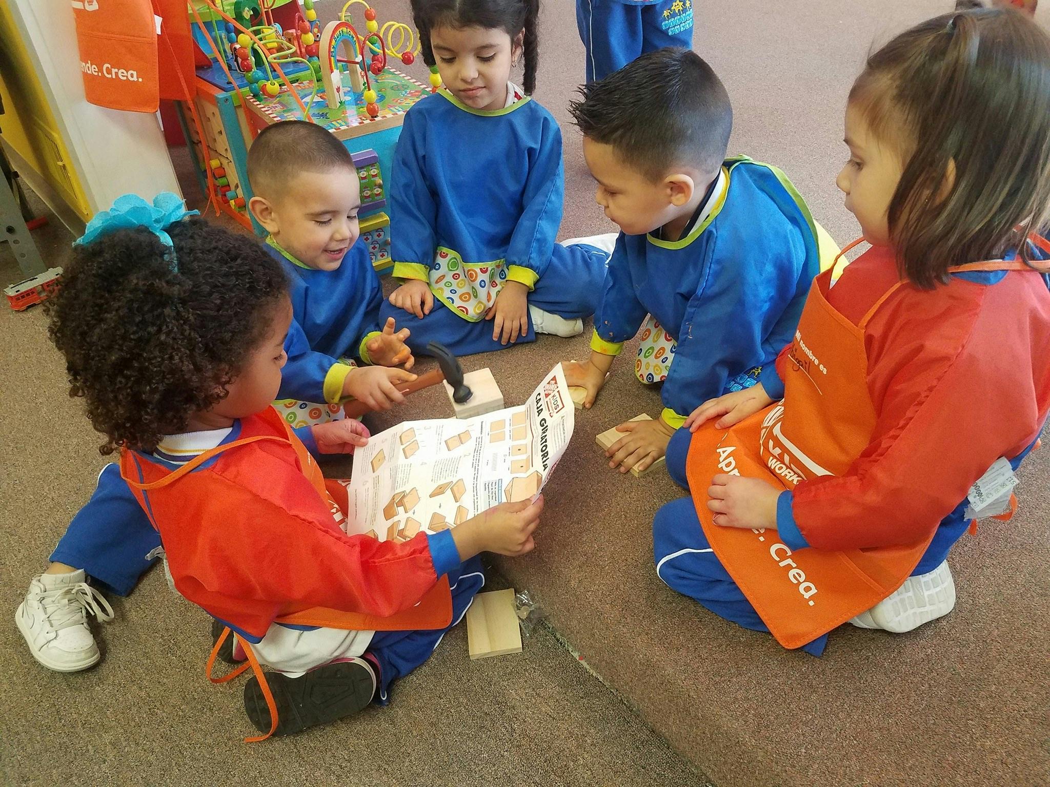 Children in blue uniforms and aprons looking at a book on the floor