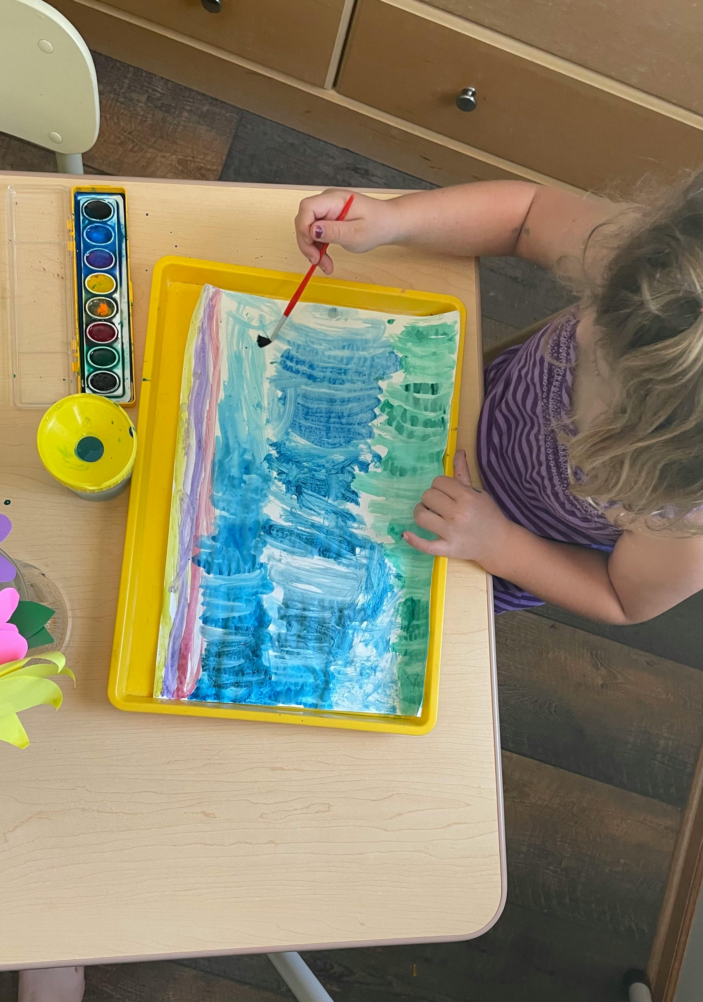 Child painting with watercolors at a table