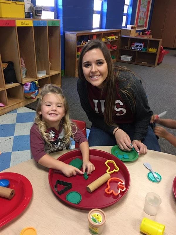Adult and child playing with play-doh and cookie cutters at a table