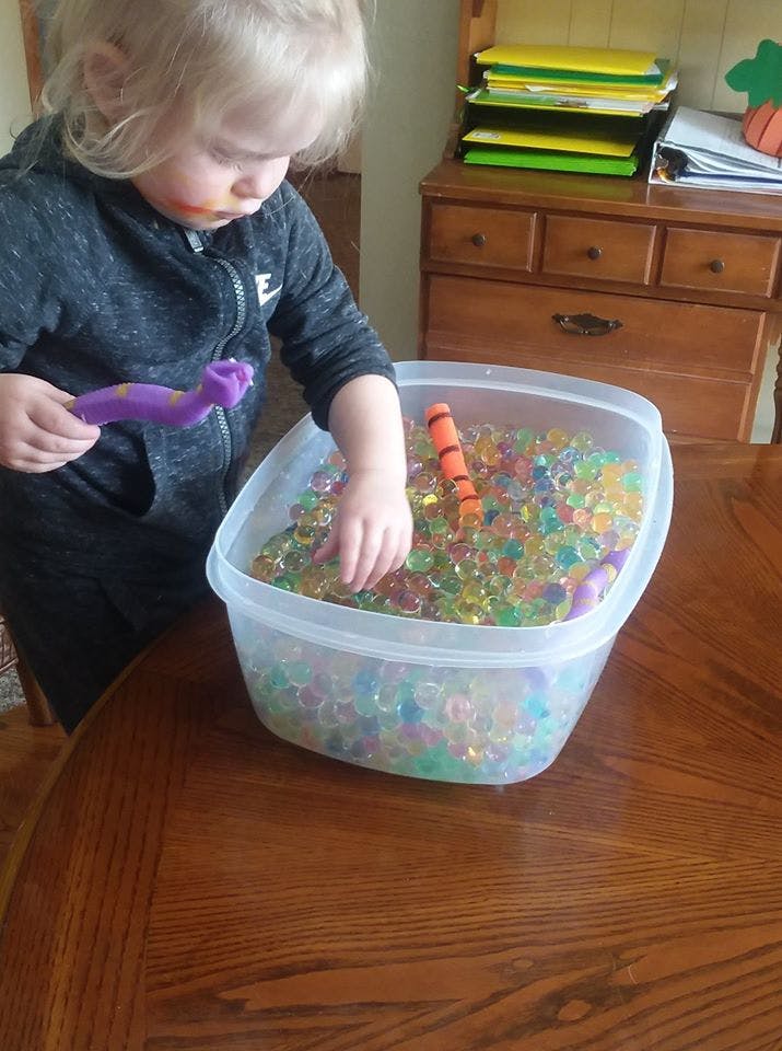 Child playing with water beads in a clear container