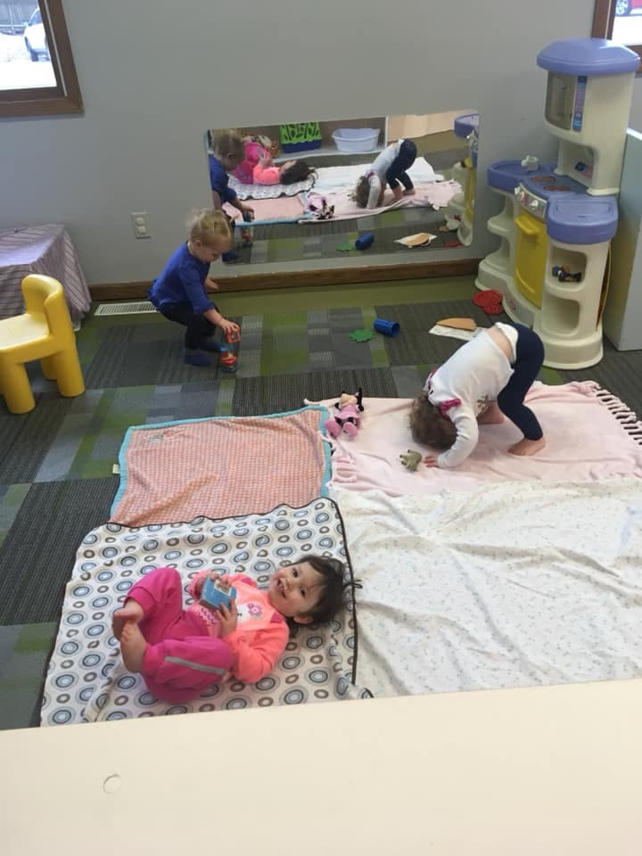 Three children playing on blankets on the floor