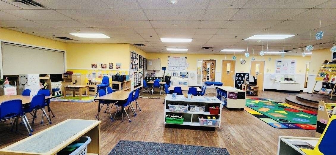 Classroom with small tables and chairs, various learning stations, and colorful rugs