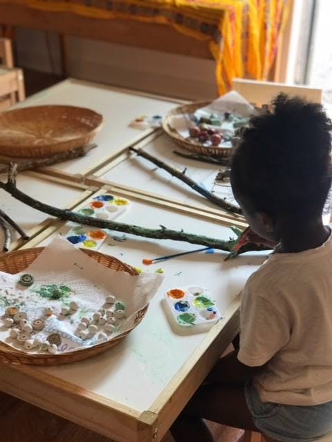 Child painting branches at a table