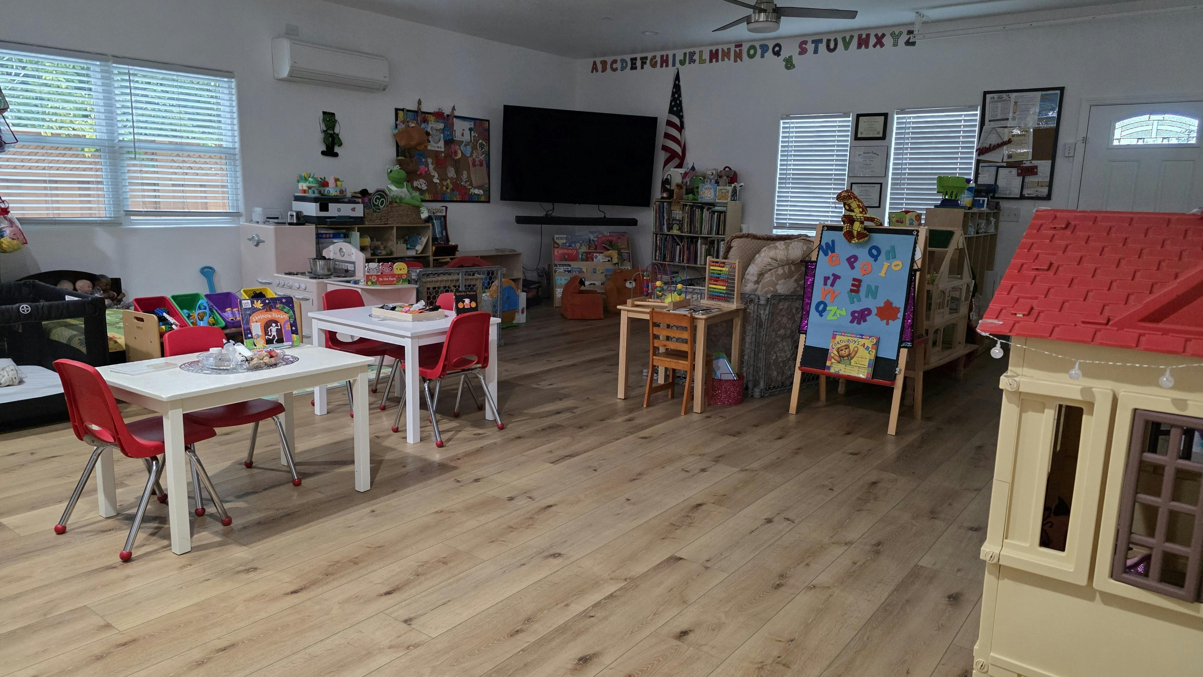 Playroom with small tables and chairs, toys, and a dollhouse