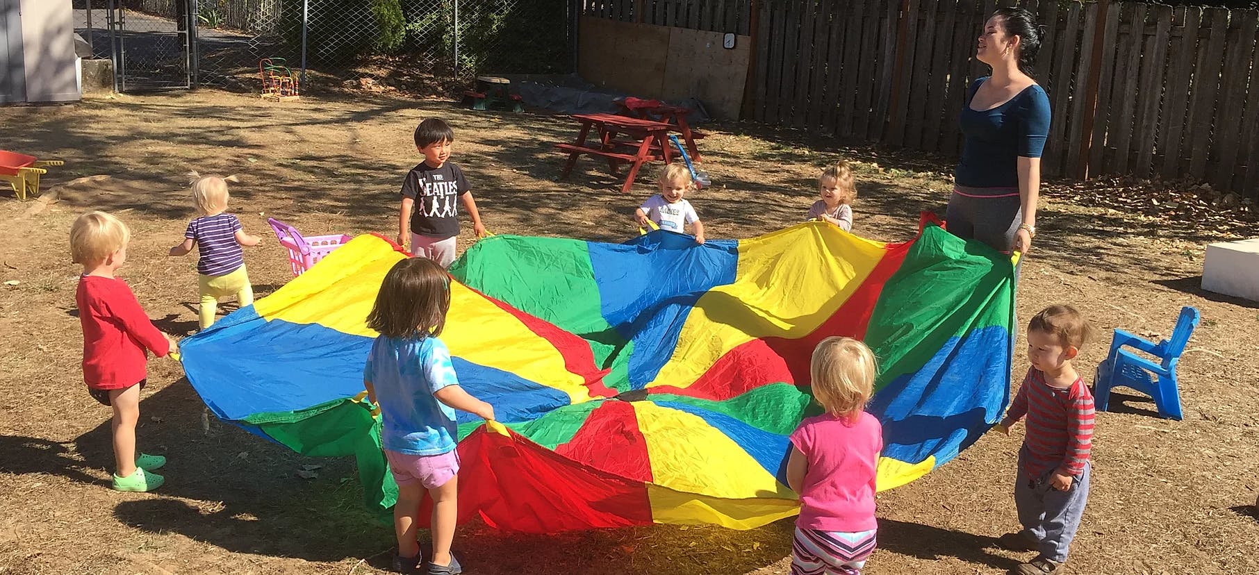 Adult and children playing with a colorful parachute outdoors