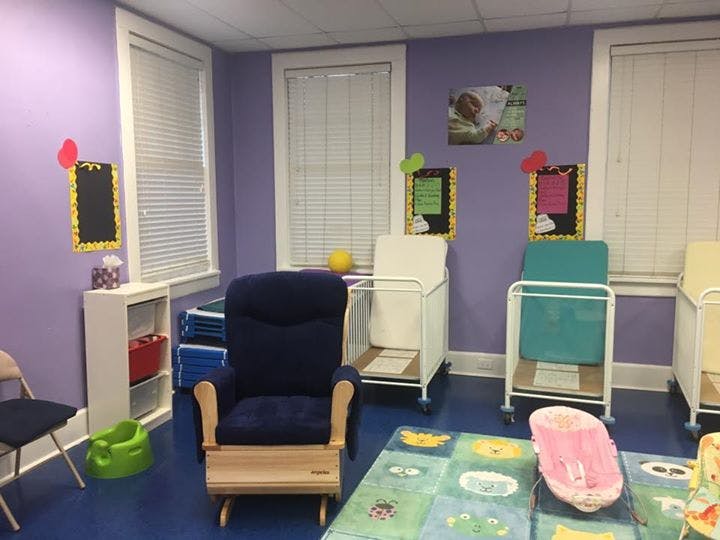 Room with purple walls, blue floor, rocking chair, and cribs
