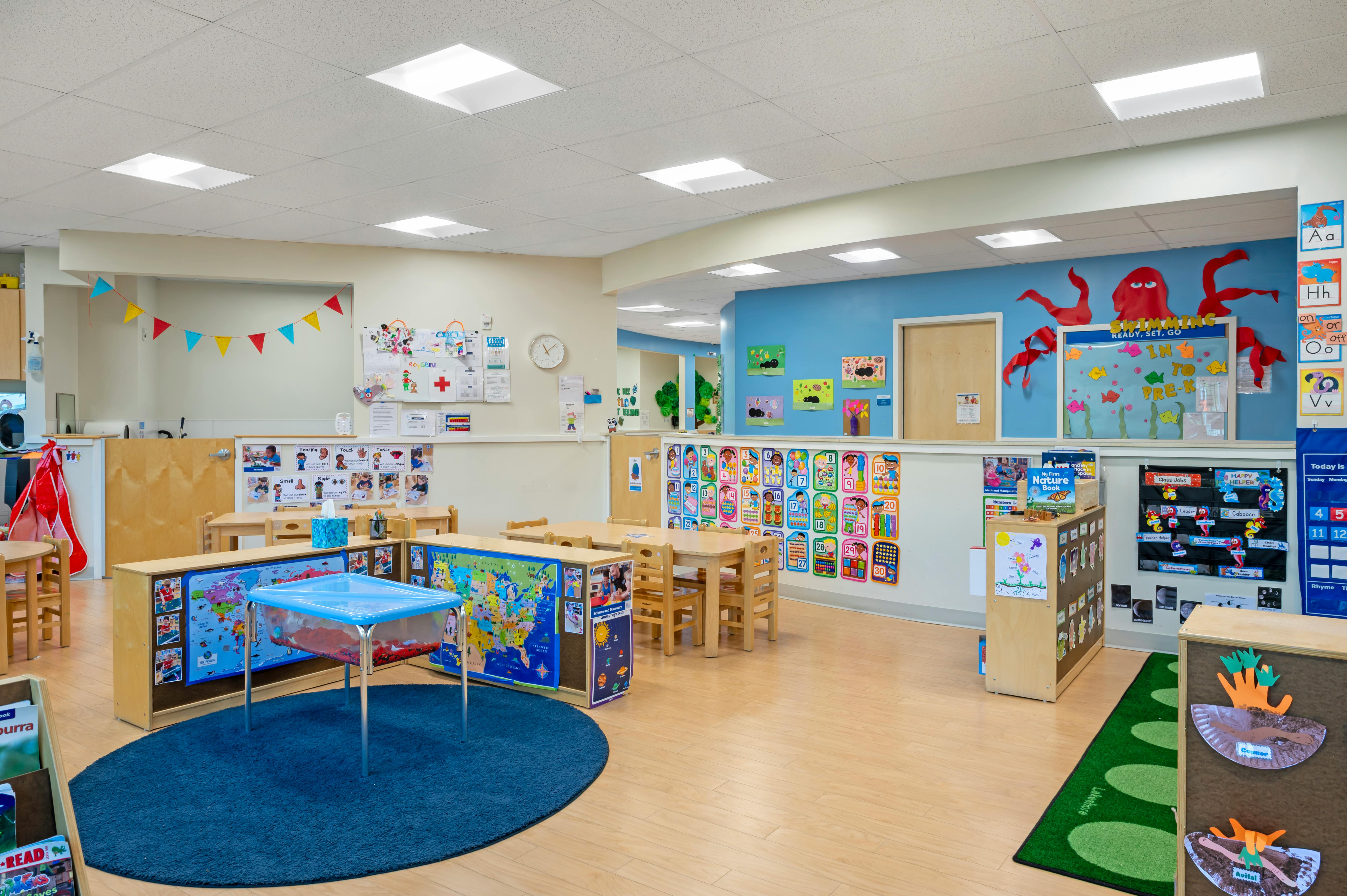 Colorful preschool classroom with learning stations and educational wall charts