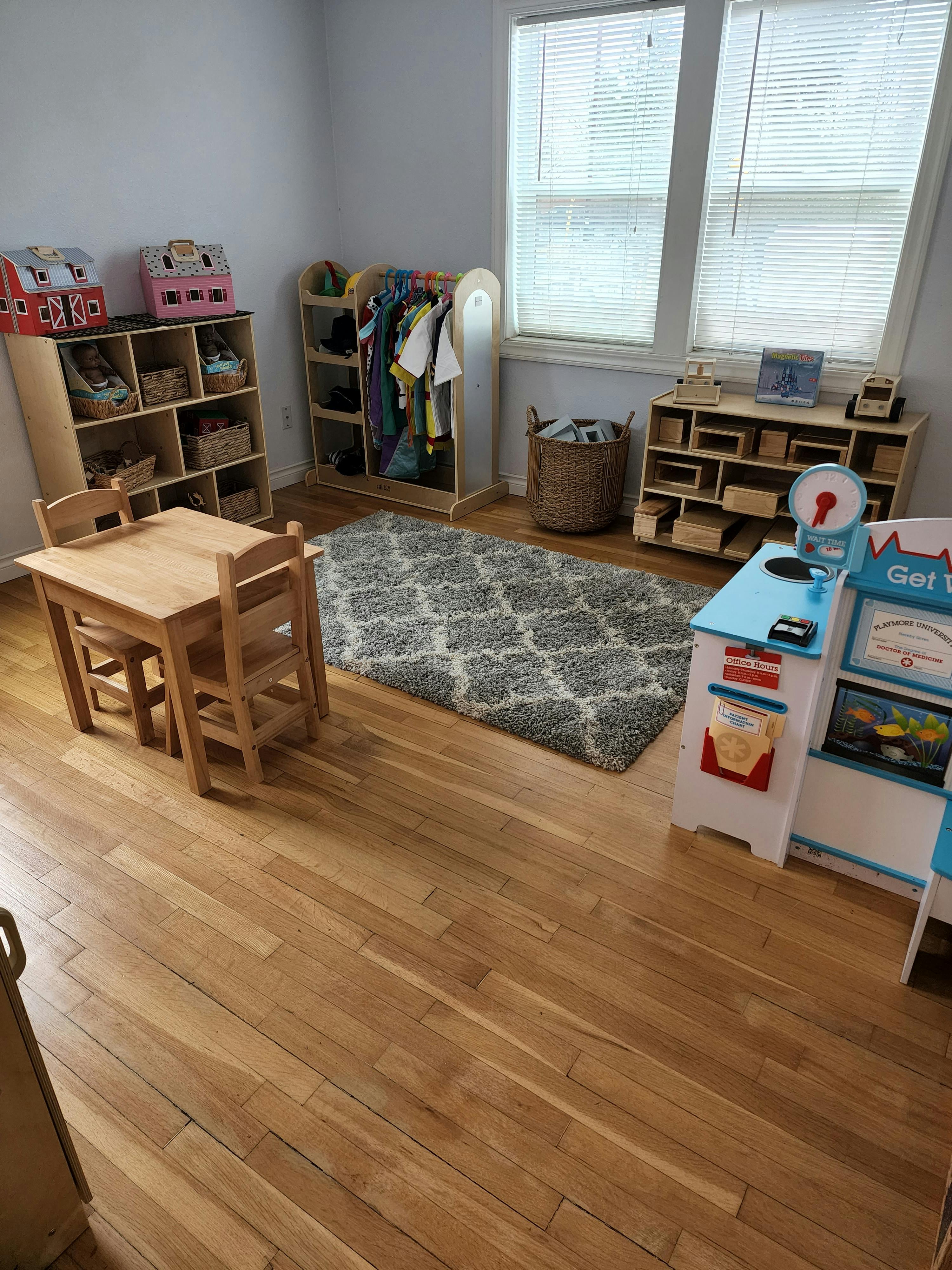 Playroom with small wooden table and chairs, shelves, and play kitchen