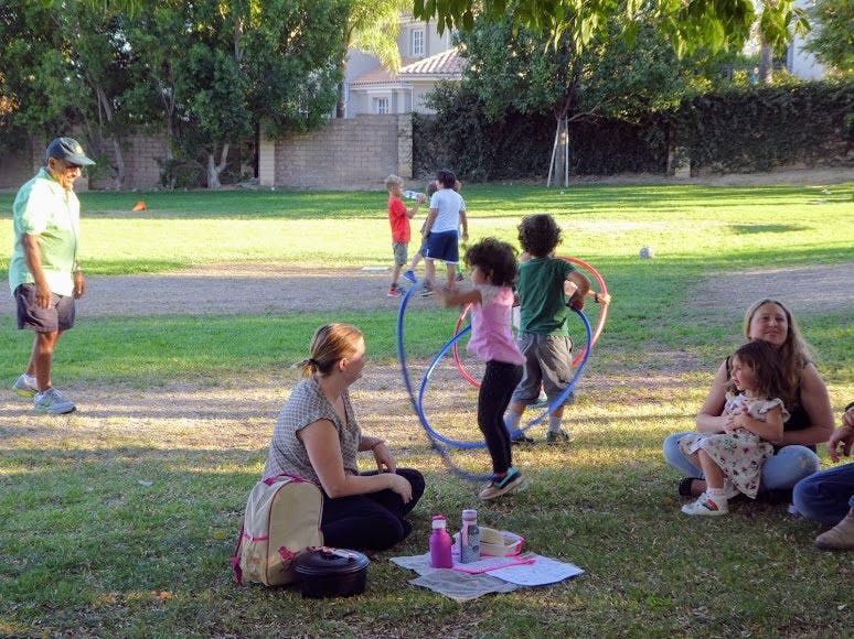 People and children playing with hula hoops in a park