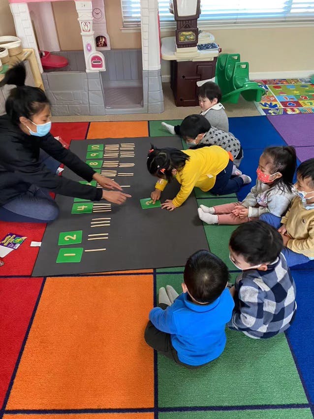 Person and children on floor with learning mat