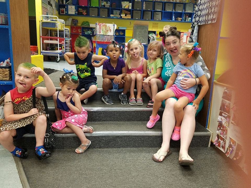 Adult and children sitting on steps in a classroom