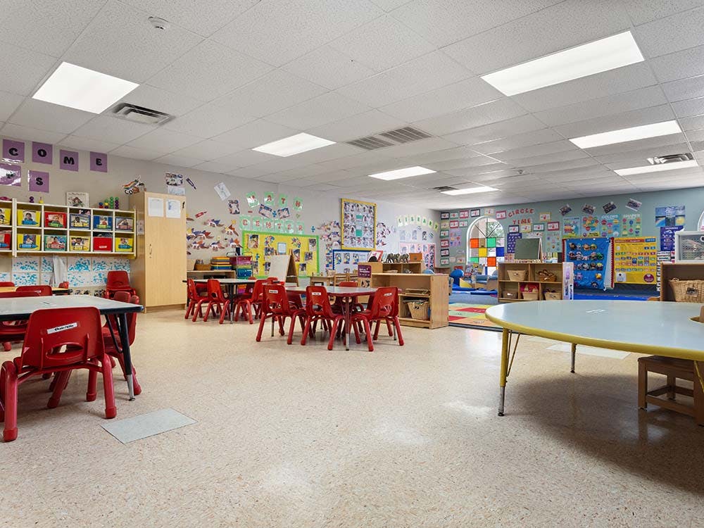 Empty classroom with small red chairs and tables