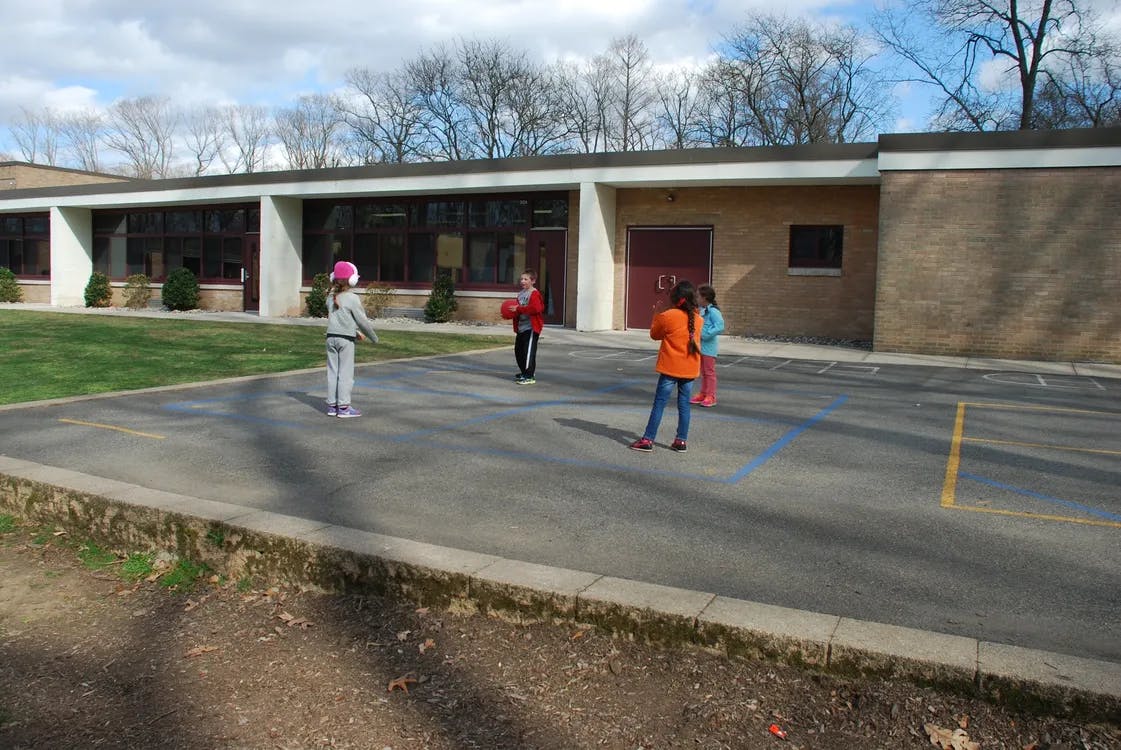 Children playing on a paved area outside a building