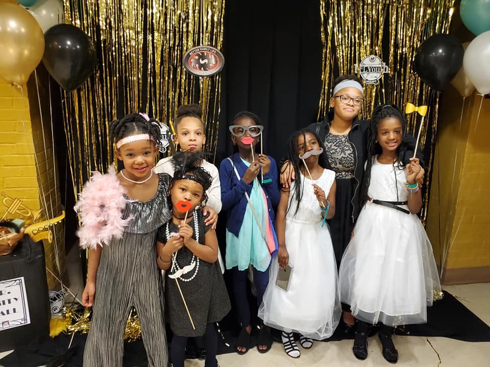 Group of children and one adult posing with photo booth props