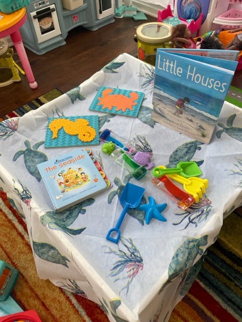 Children's books, sand toys, and sea creature cutouts on a table