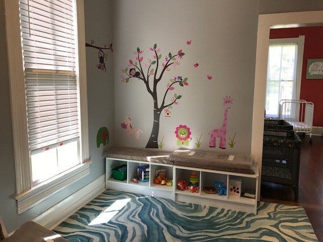 Playroom with tree and animal wall decals above storage bench