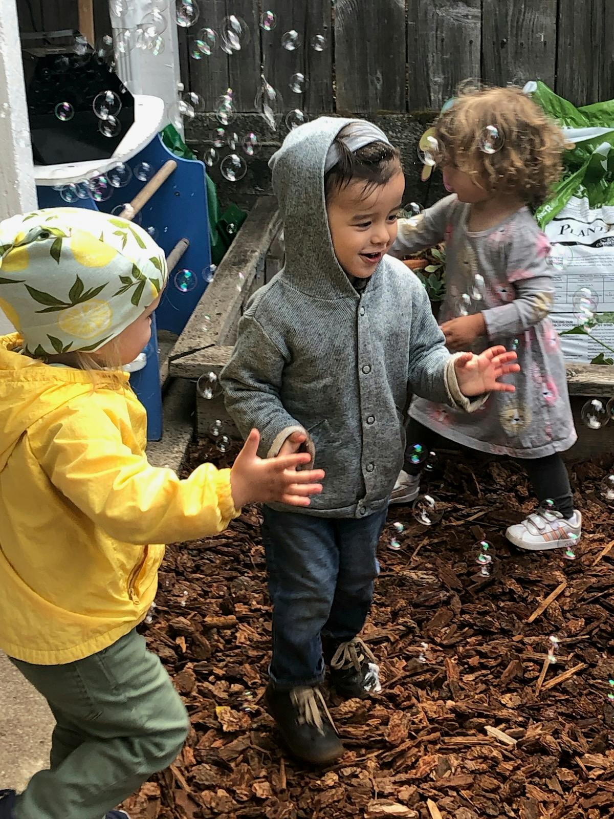 Three children playing outdoors with bubbles
