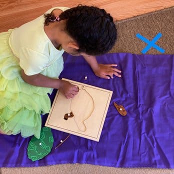 Child playing with a wooden puzzle on a purple mat