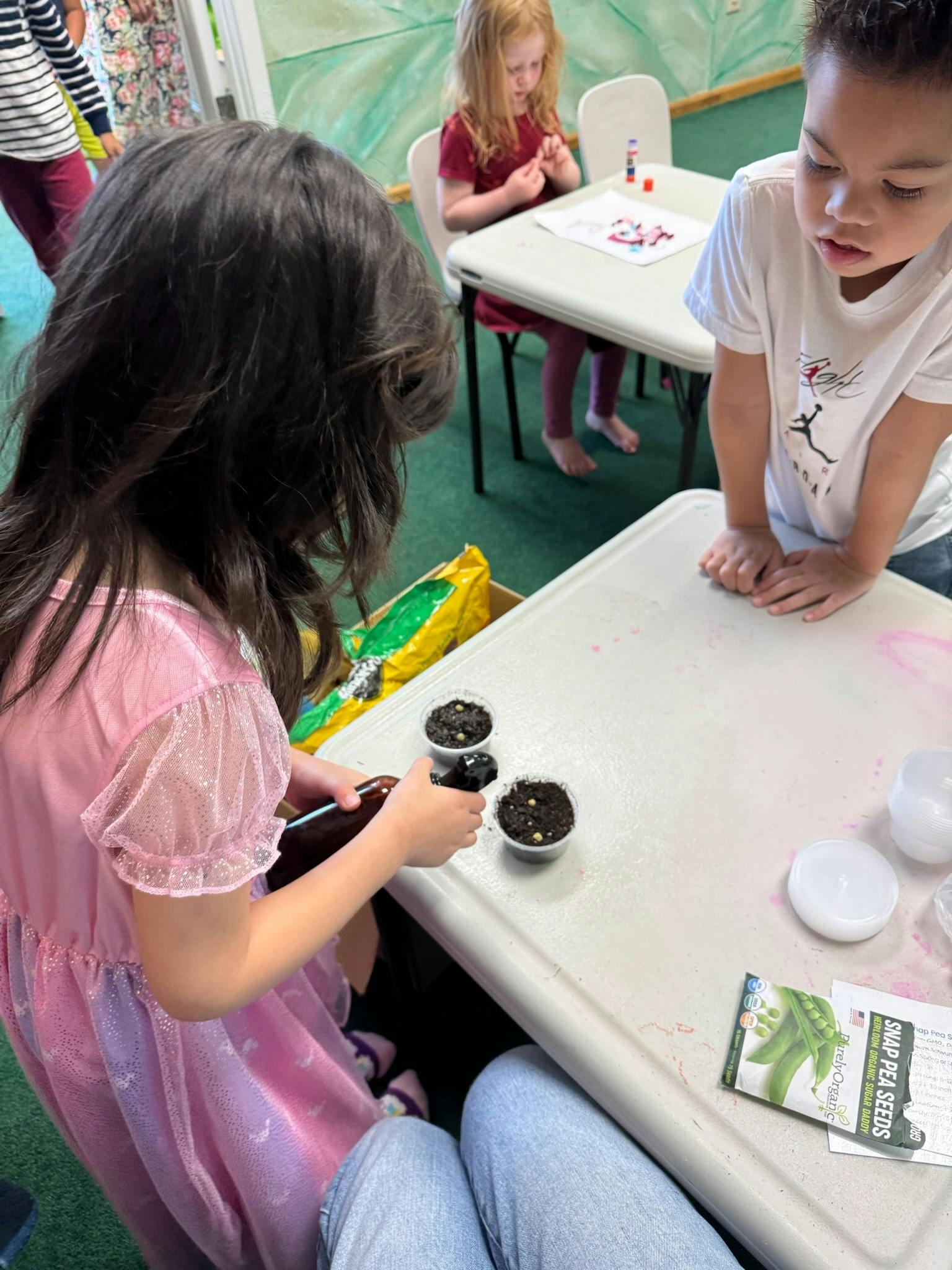 Children planting seeds in small pots at a table