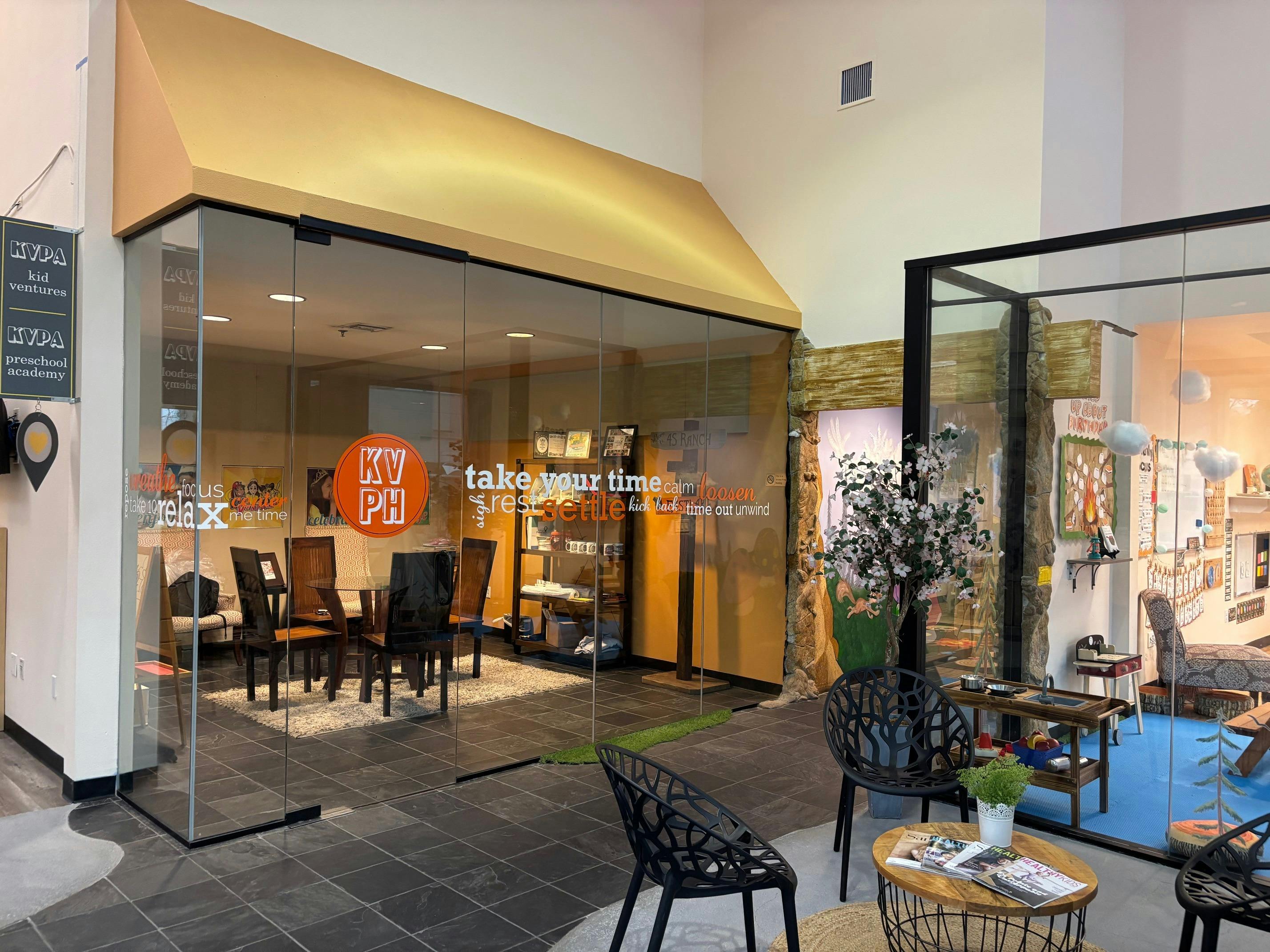 Glass storefront with a gold awning and a seating area inside