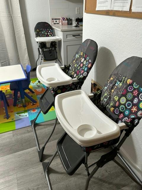 Three children's high chairs with floral patterns in a room