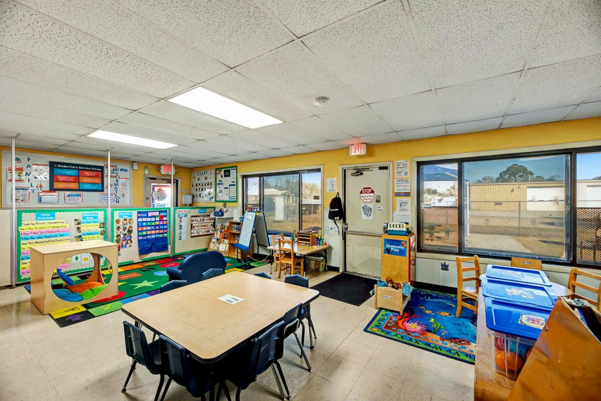 empty preschool classroom with tables, chairs, and colorful decorations