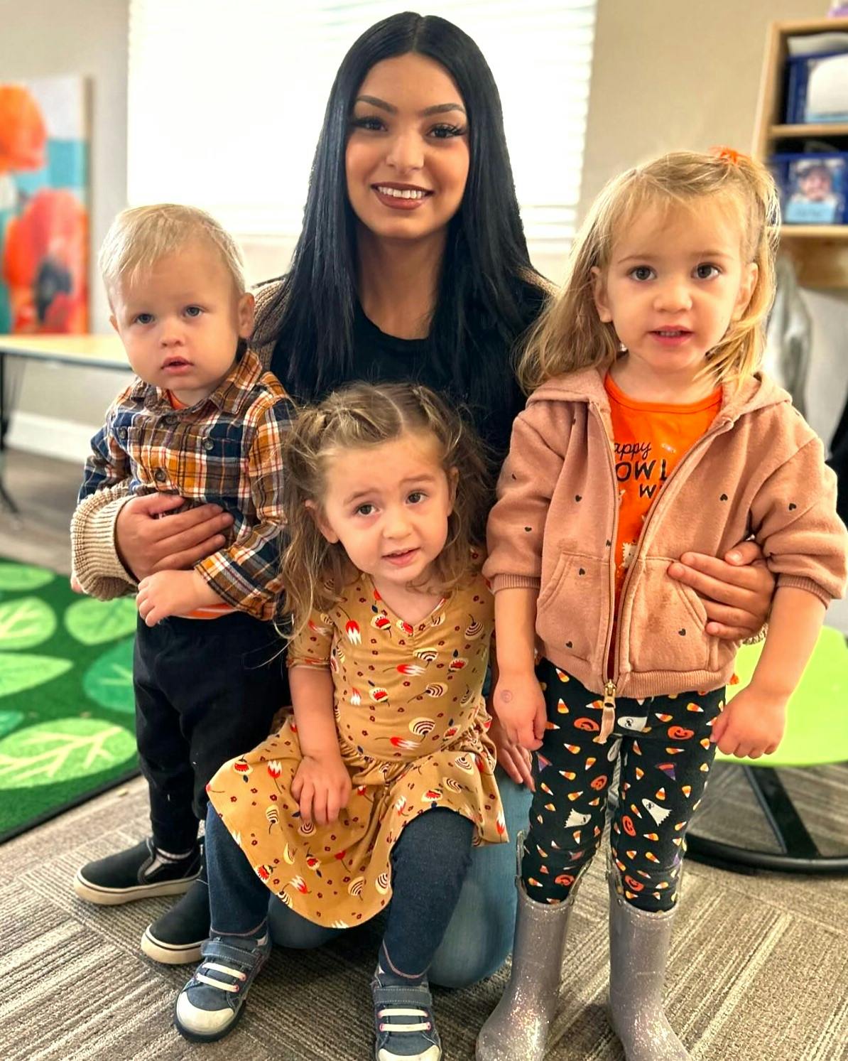 Person with three children in a classroom
