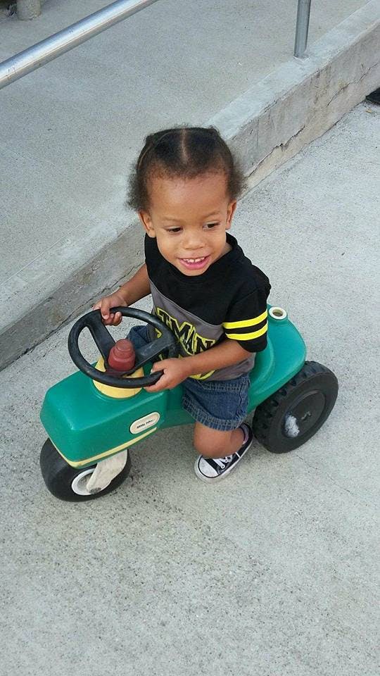 Child on a green toy tractor