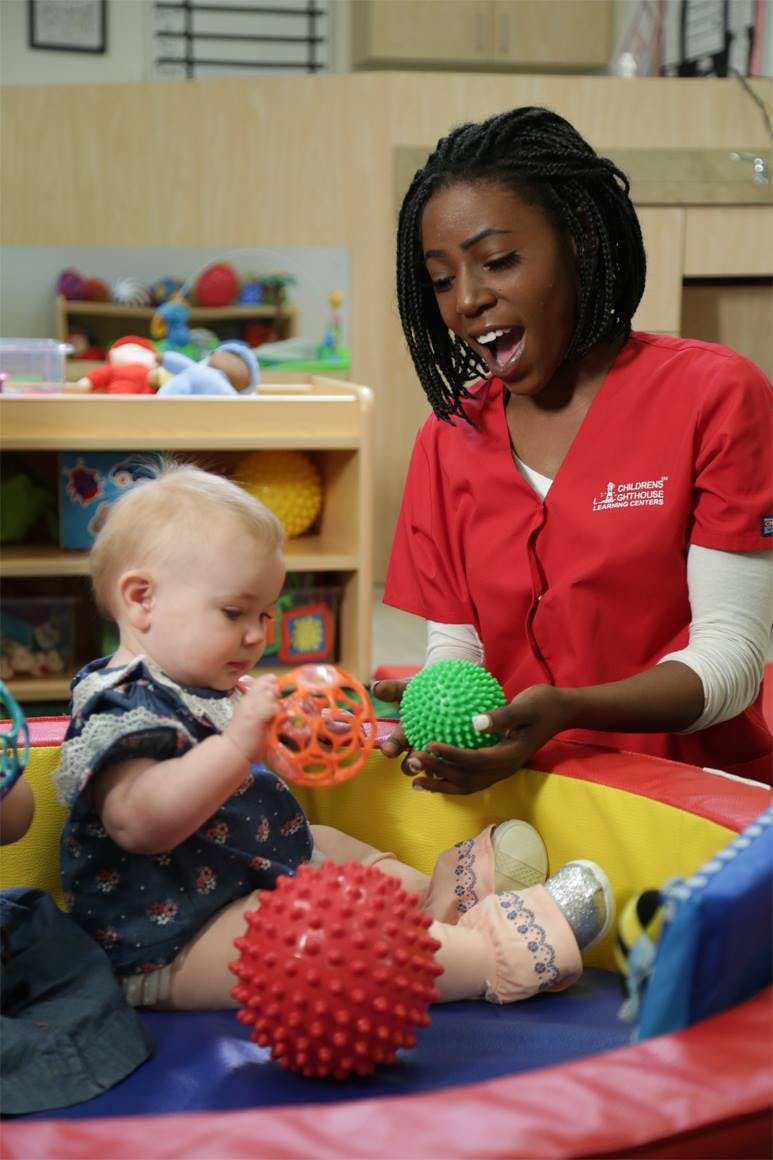 Person in red scrubs playing with a child and textured balls