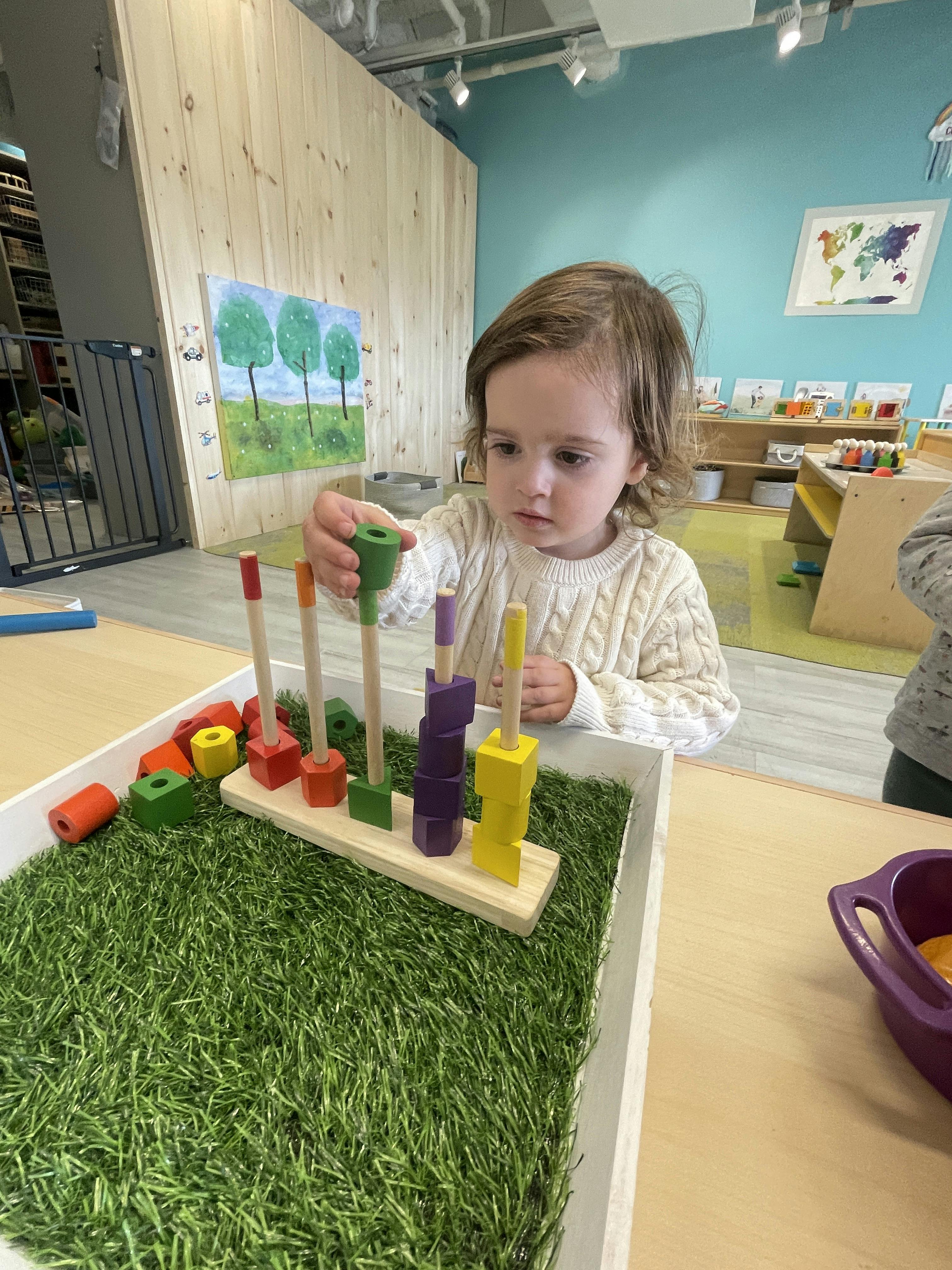 Child playing with a wooden stacking toy in a classroom