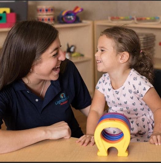 Adult and child looking at each other across a table with a toy